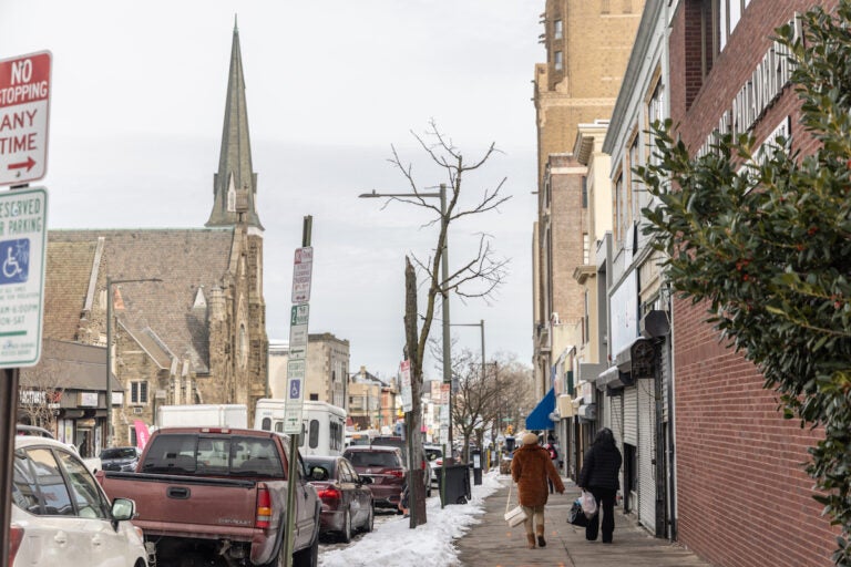 People walk down the sidewalk at Chelten Ave. and Greene St. in Germantown