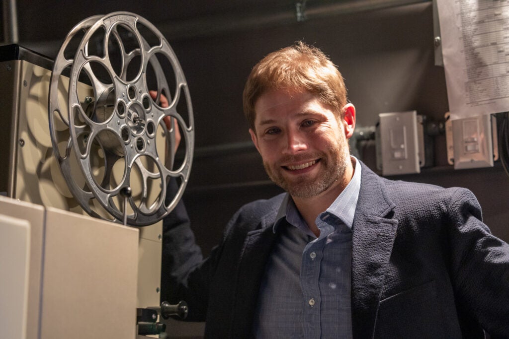 Christopher Collier poses next to a projector