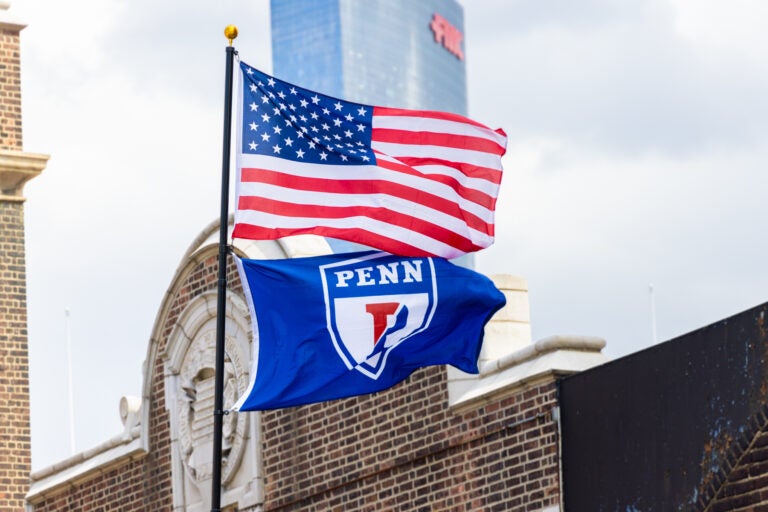 An American flag flying with a Penn flag