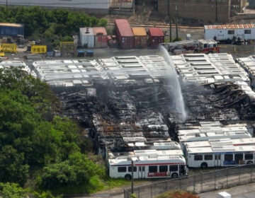 an aerial view of water being sprayed over the burned SEPTA buses