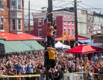 Many onlookers watch people climbing a greased pole
