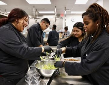 Several people working together on a salad in a kitchen