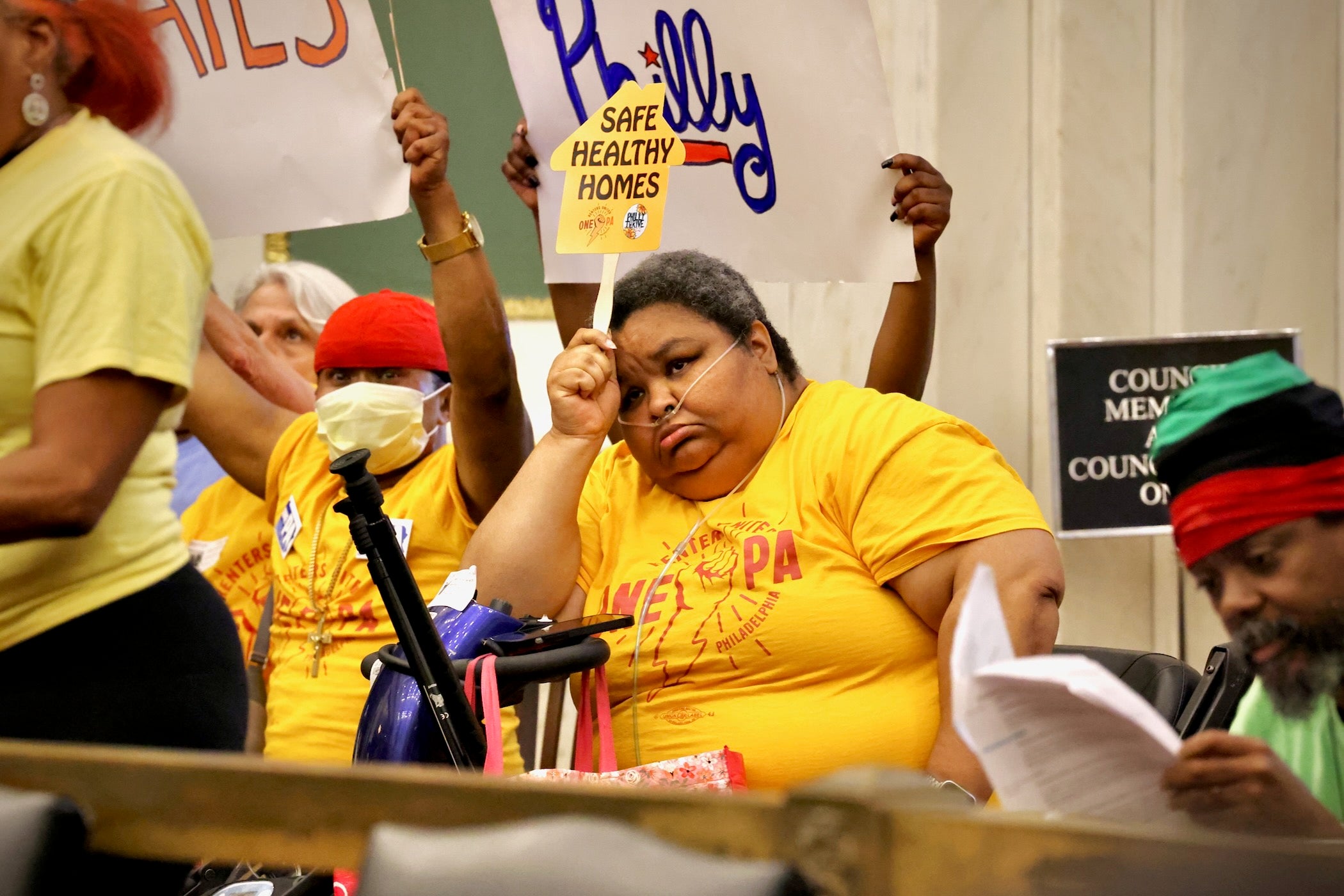 Melissa holds a sign reading SAFE HEALTHY HOMES
