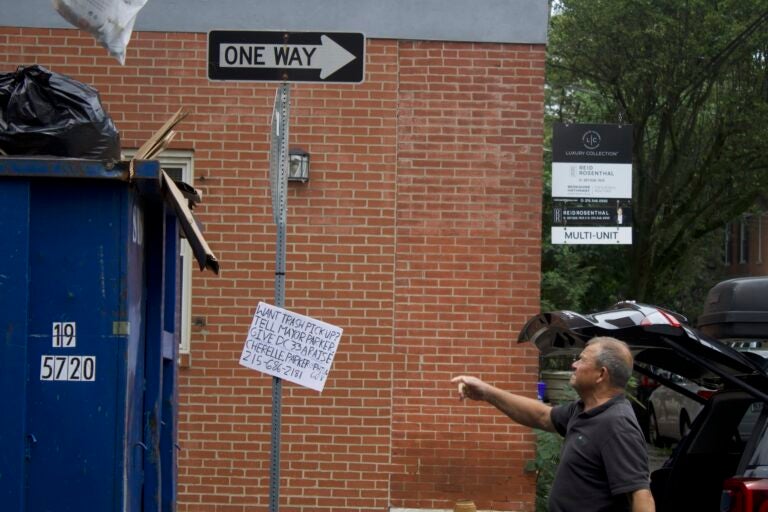 A person throws trash in a dumpster at Catharine and 18th streets in Philadelphia