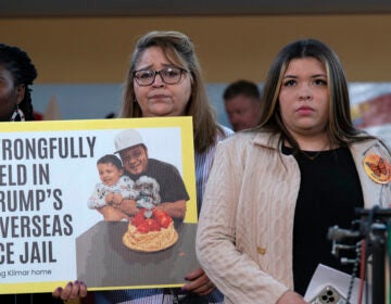 A woman stands with a sign that reads 
