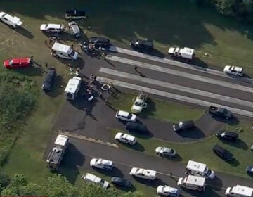 A large number of vehicles for medical personnel and first responders sit on a runway at an airport following a report of a plane crash