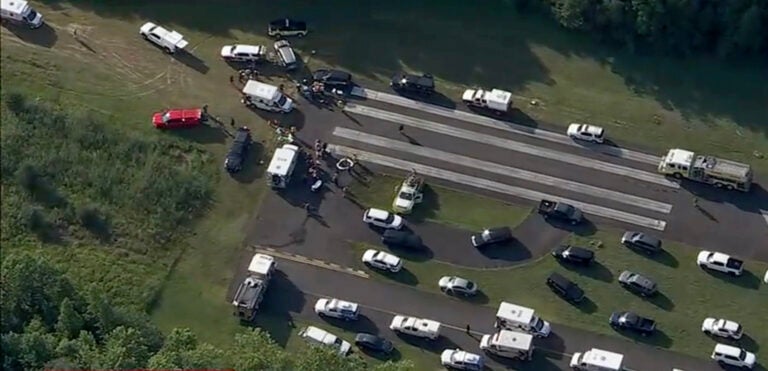 A large number of vehicles for medical personnel and first responders sit on a runway at an airport following a report of a plane crash