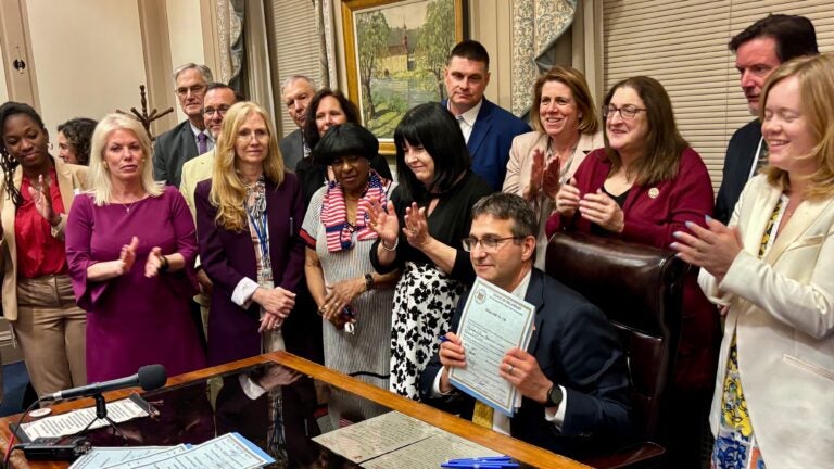 Matt Meyer holds up signed fiscal year 2026 budget legislation
