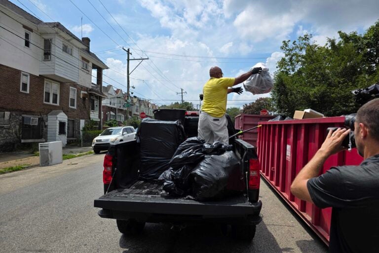 Frank Tingle throws trash into dumpster