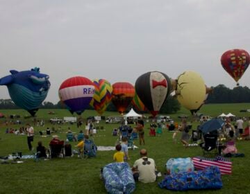 Several hot air balloons sit on the ground at the Chester County Balloon Festival. (Davis Cuffe/WHYY)