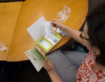 Dr. Allison Kolpas, a professor in the math department at West Chester University, opens her DNA testing packet. (Emily Cohen for WHYY)