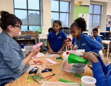 Kate Testa helps four students with puppets
