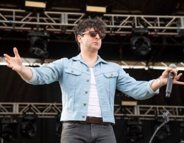 Adam Weiner on stage holding his hands up to the crowd