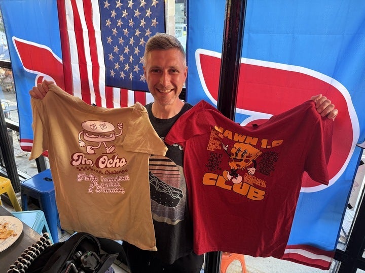 Max Stanford holds two shirts at Bar Jawn in Manayunk