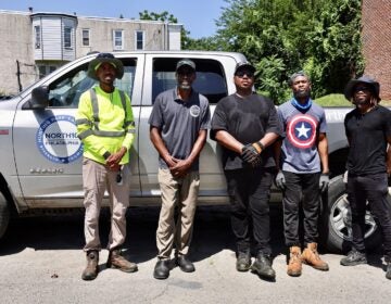 A group of men in work clothes posing for a photo standing in front of a pickup truck