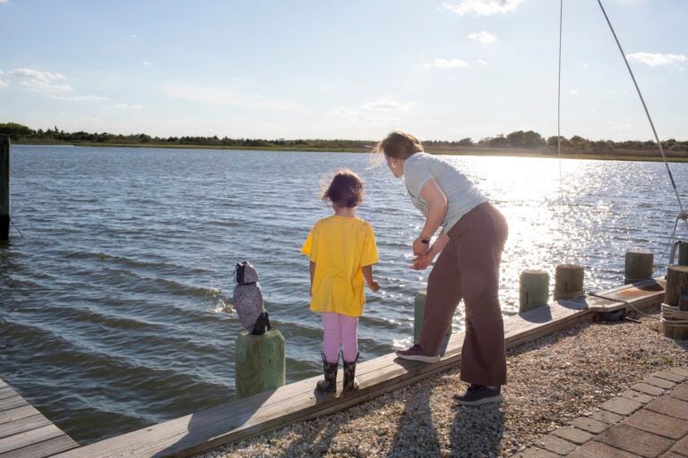 A mother and daughter skipping rocks into the water