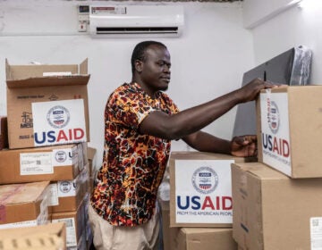 pharmacist Joseph Njer Airo inspects boxes of antiretroviral drugs labeled USAID