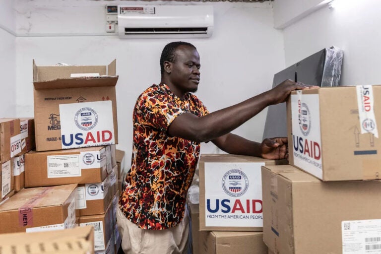 pharmacist Joseph Njer Airo inspects boxes of antiretroviral drugs labeled USAID
