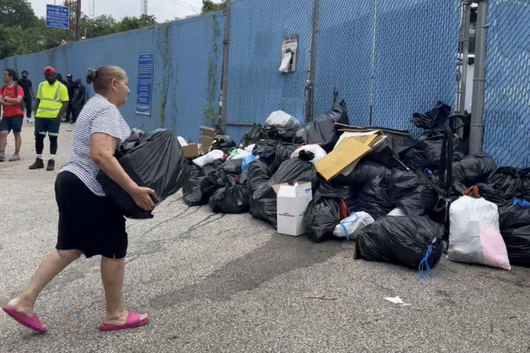 A resident drops off their trash at a temporary dump site on Domino Lane in Northwest Philadelphia during the AFSCME DC33 strike on July 2, 2025.